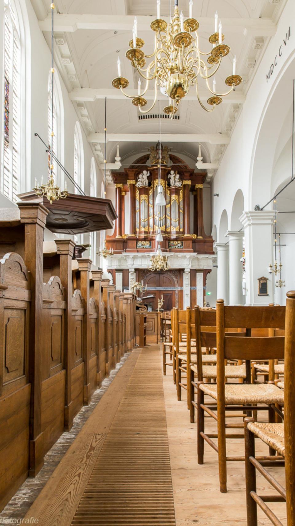 Binnenkant kapelkerk Alkmaar met houten banken en kroonluchter